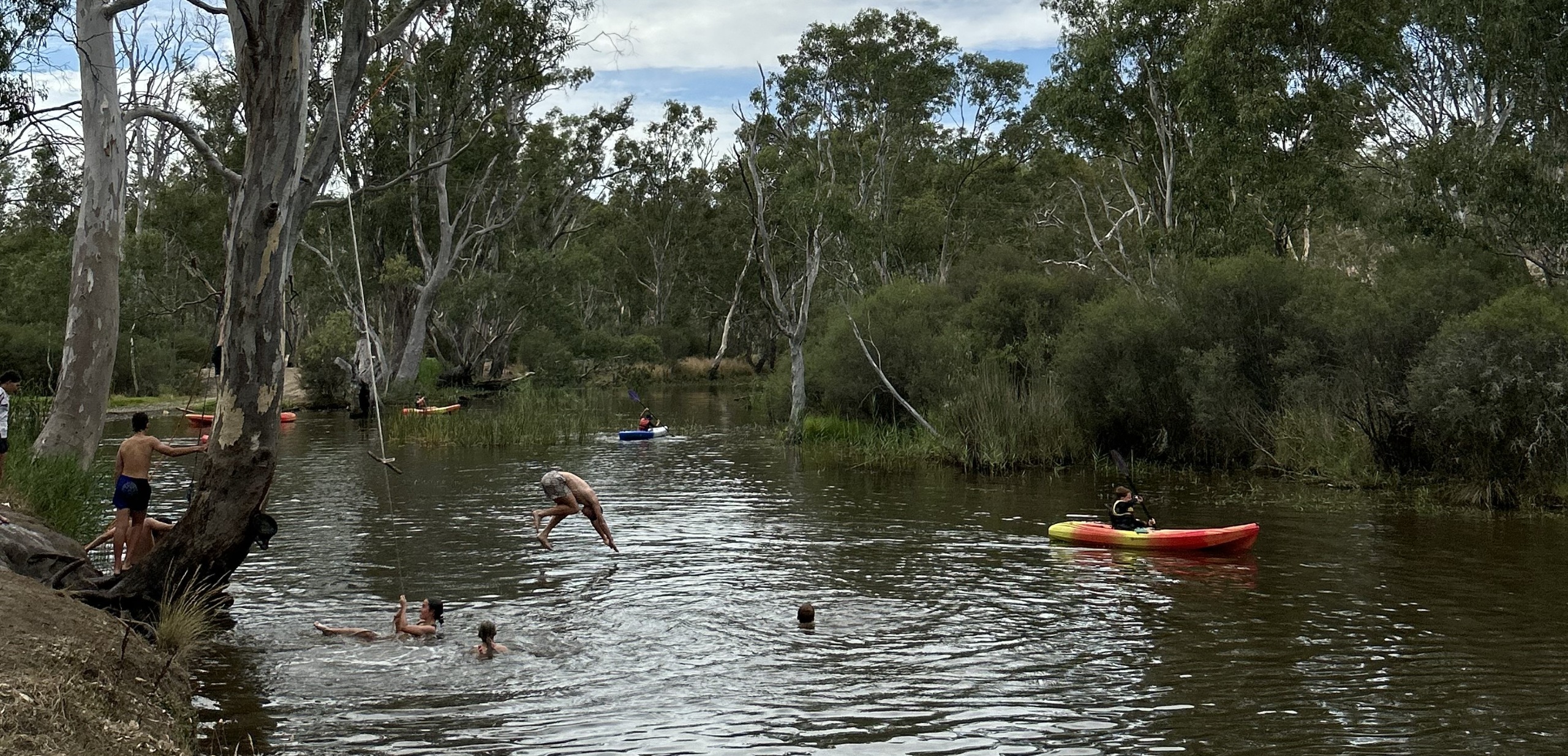 People canoeing and jumping into a river